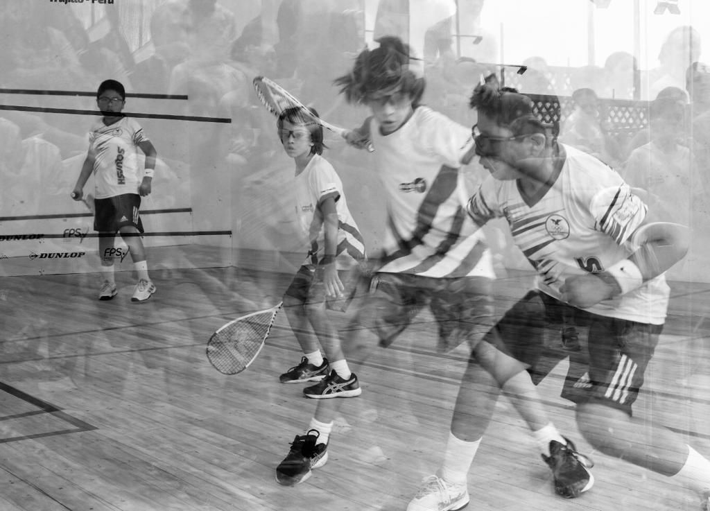 Um grupo de pessoas está jogando squash em uma quadra de madeira.