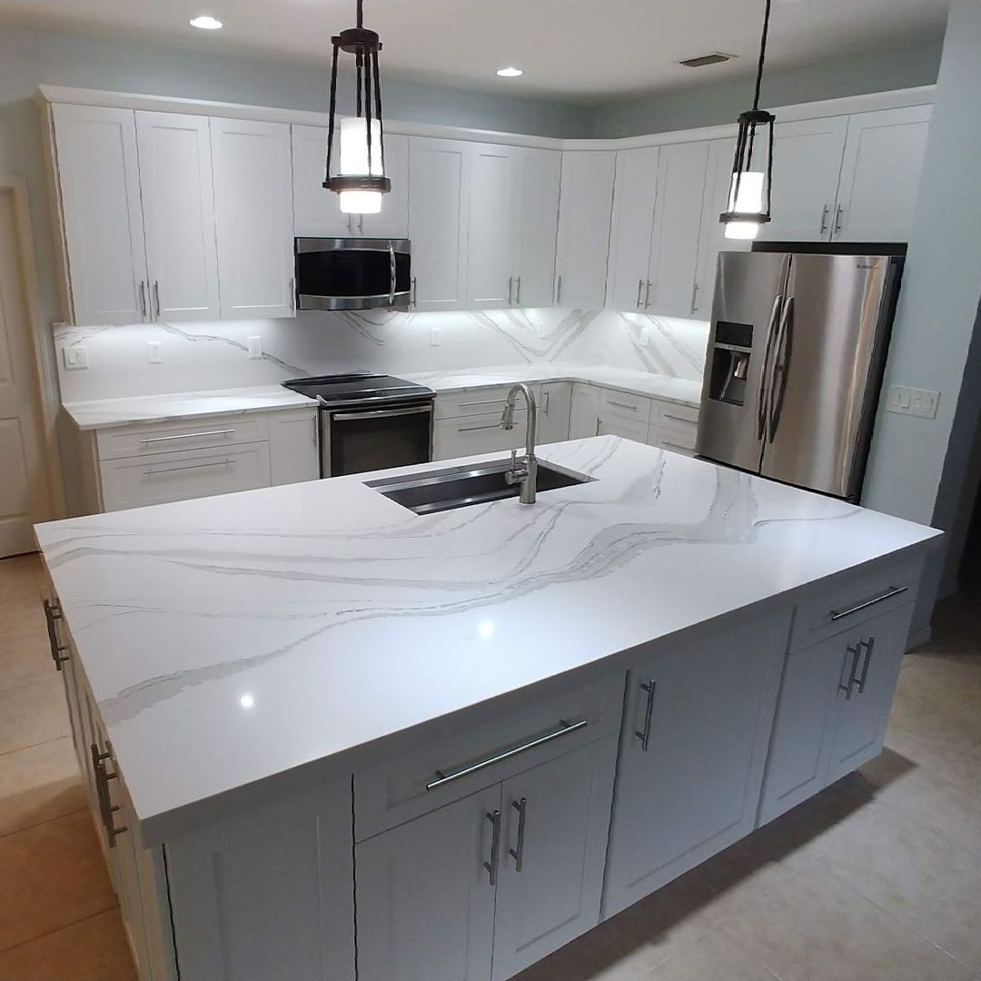 A kitchen with white cabinets , stainless steel appliances , and a large island.