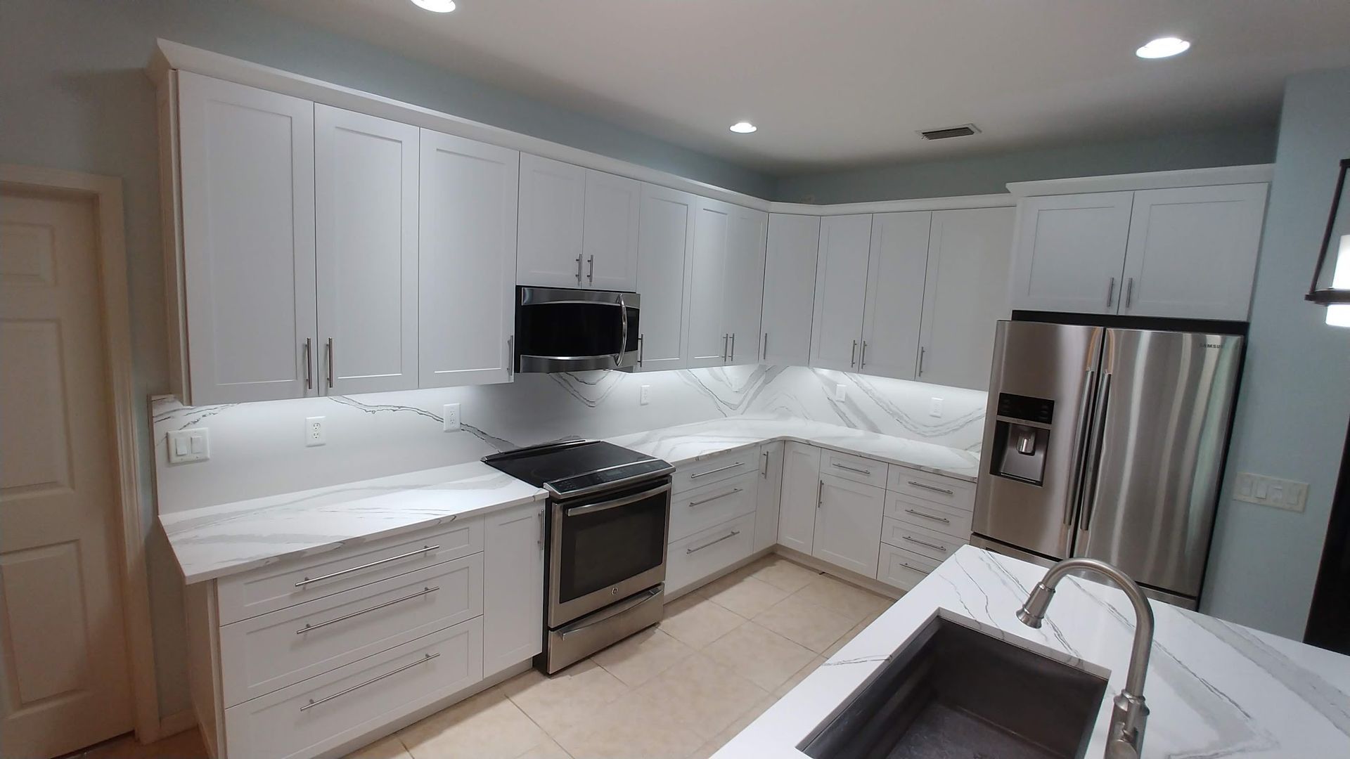 A kitchen with white cabinets , stainless steel appliances , and a sink.