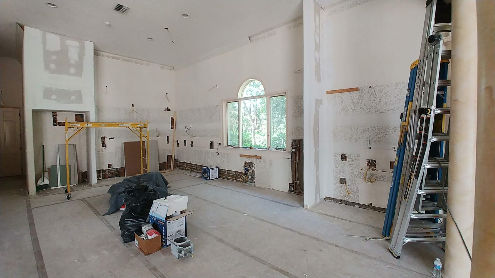 A large empty room with a ladder in the middle of it.