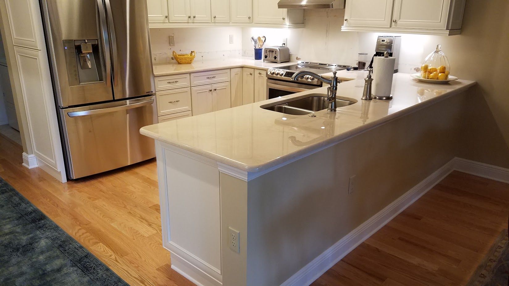 A kitchen with white cabinets , stainless steel appliances , a sink , and a refrigerator.