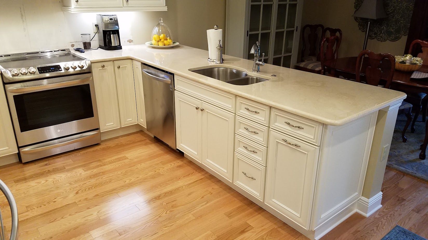 A kitchen with white cabinets , stainless steel appliances , a sink and a stove.