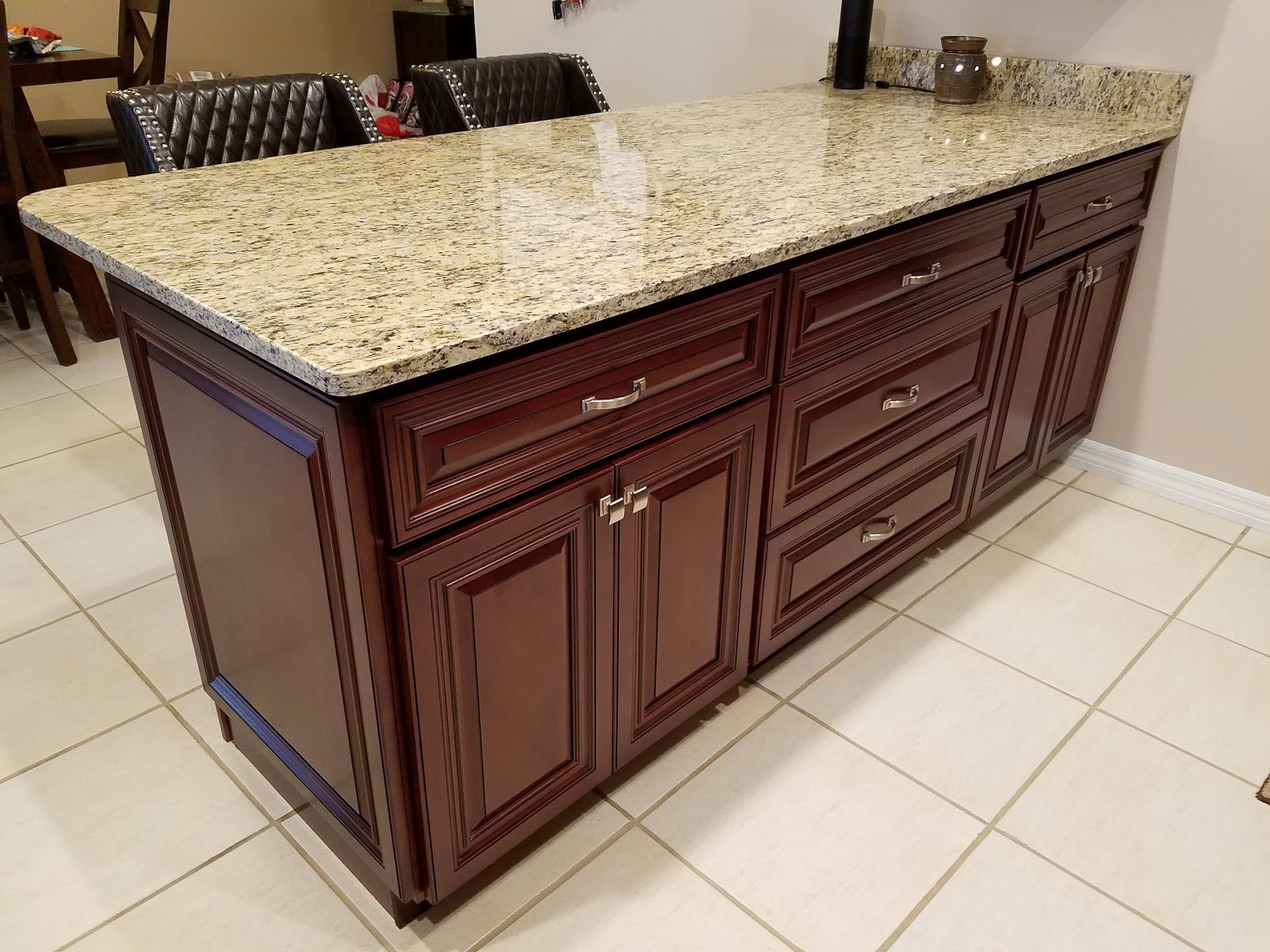 A kitchen island with granite counter tops and wooden cabinets.