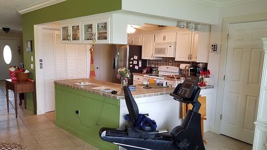 A kitchen with green cabinets and a treadmill on the counter.