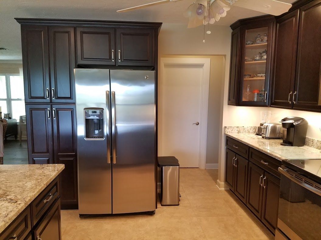 A kitchen with stainless steel appliances and dark cabinets
