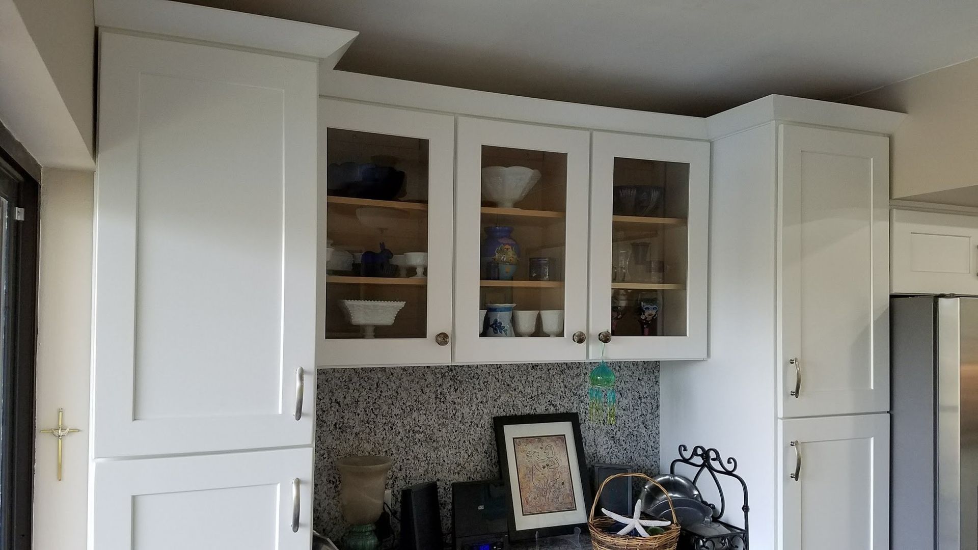 A kitchen with white cabinets and glass doors