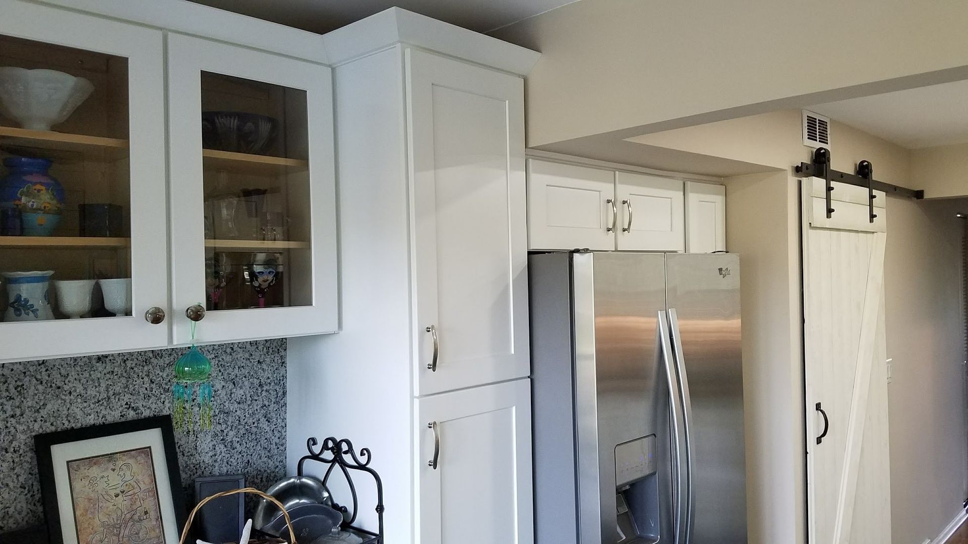 A kitchen with white cabinets and a stainless steel refrigerator