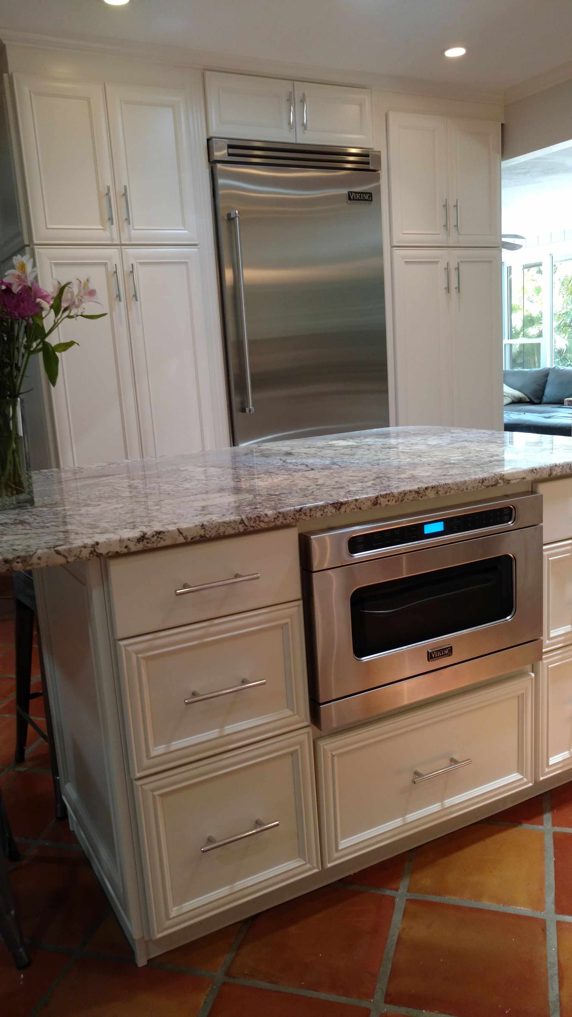 A kitchen with white cabinets , a stainless steel refrigerator , and a stainless steel oven.