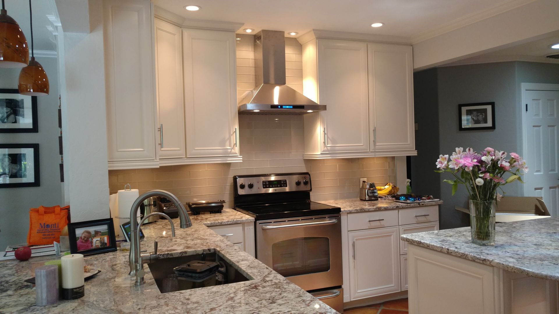 A kitchen with white cabinets , granite counter tops , stainless steel appliances and a sink.