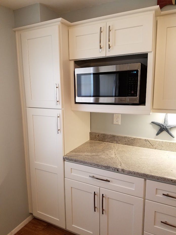 A kitchen with white cabinets and a stainless steel microwave.