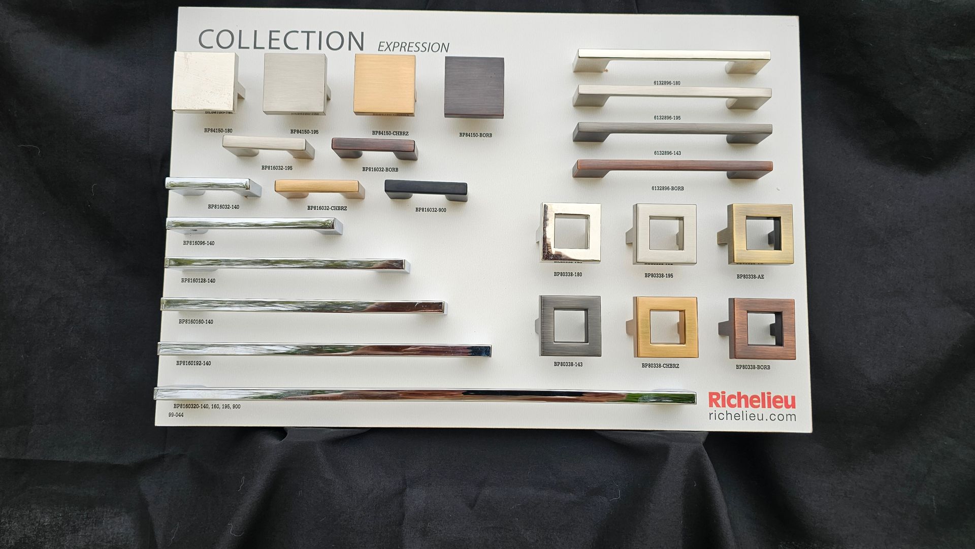 A collection of cabinet handles is displayed on a black cloth