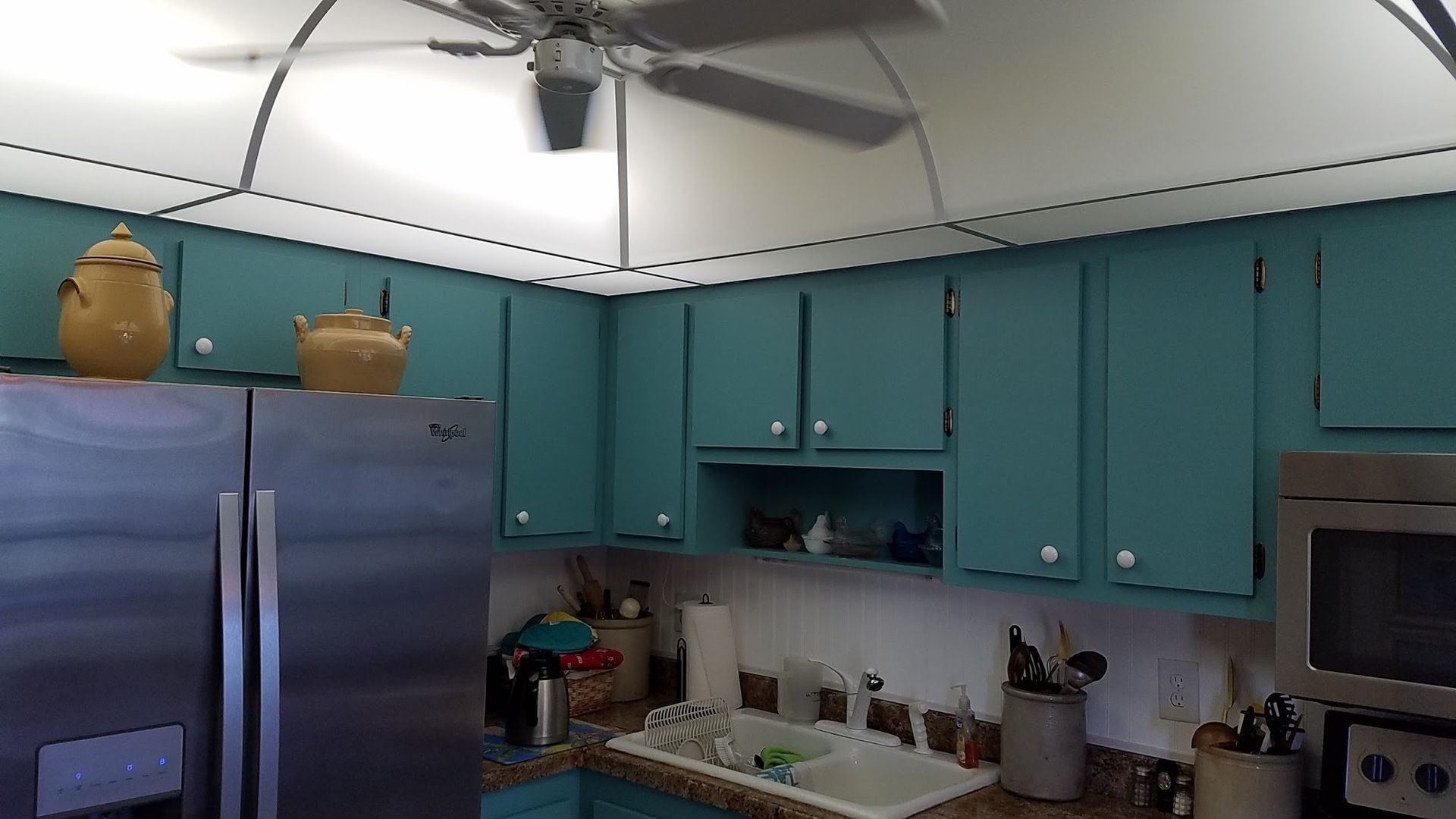 A kitchen with blue cabinets and a ceiling fan