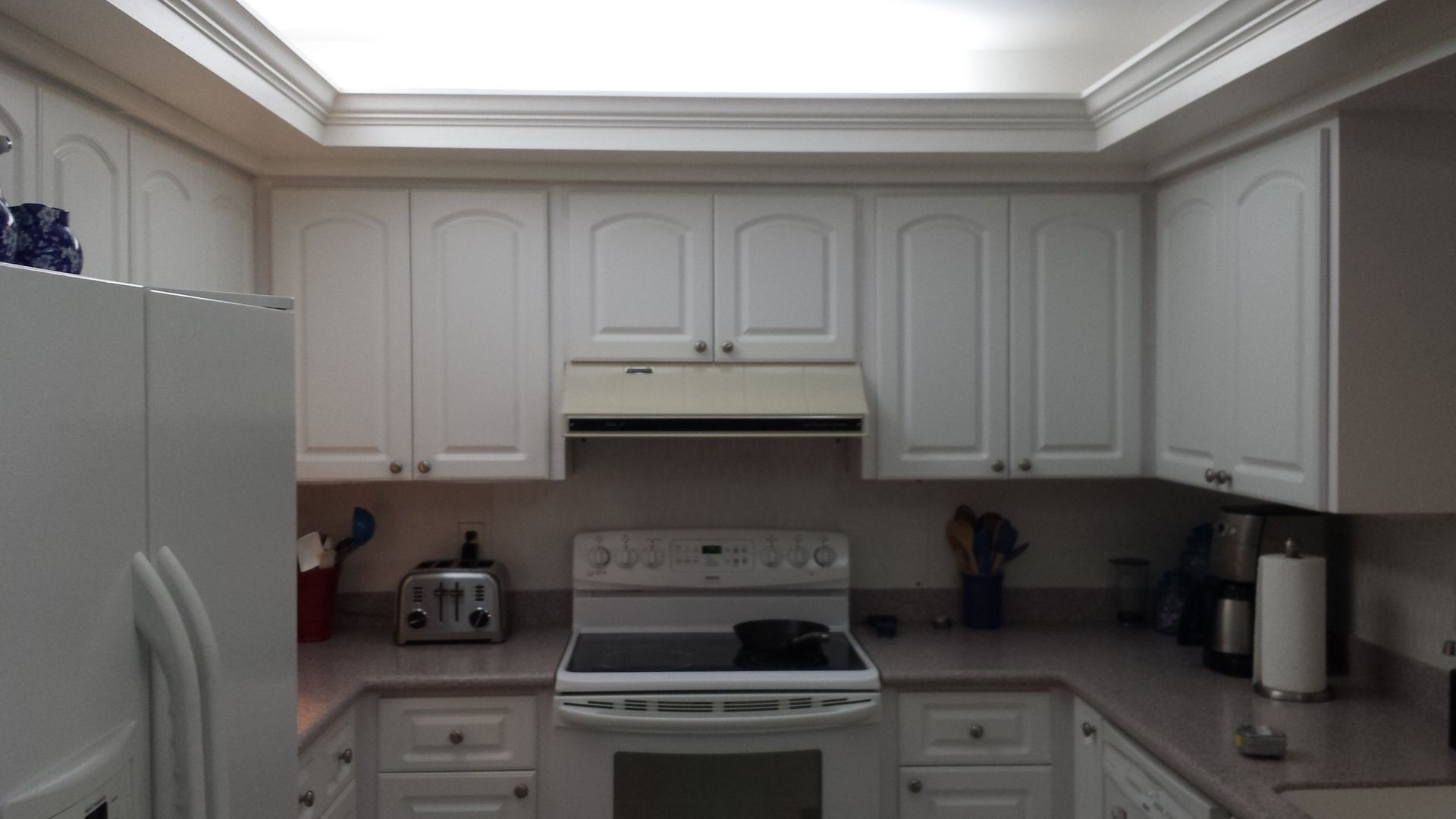A kitchen with white cabinets and a stove top oven