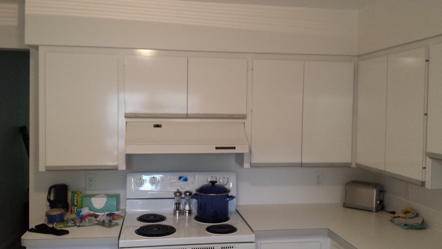 A kitchen with white cabinets and a stove top oven