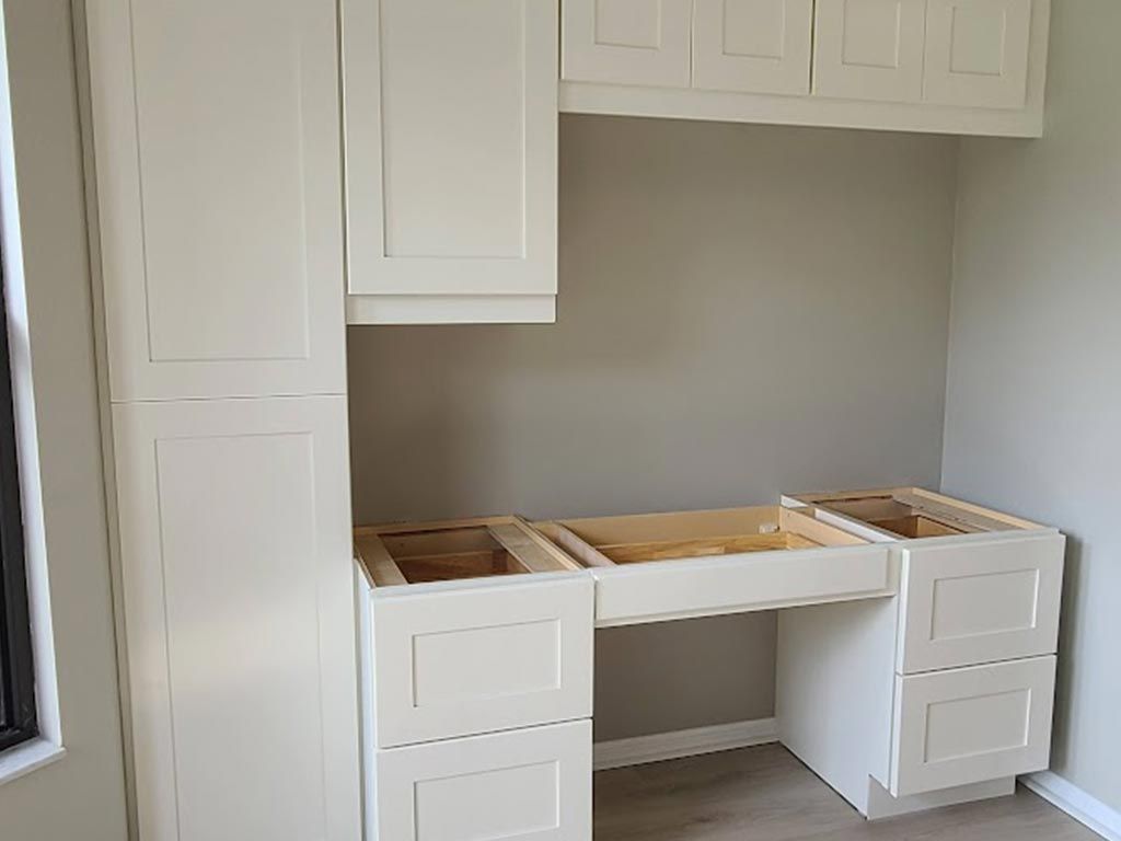 A room with white cabinets and a desk in it.