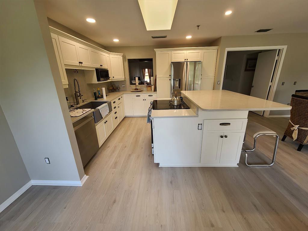 A kitchen with white cabinets , stainless steel appliances , and a large island.