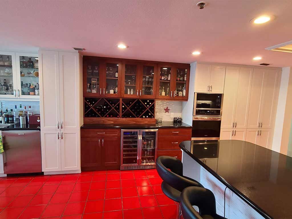 A kitchen with red tile floors and a black counter top