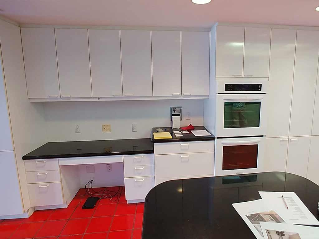 A kitchen with white cabinets and a black counter top