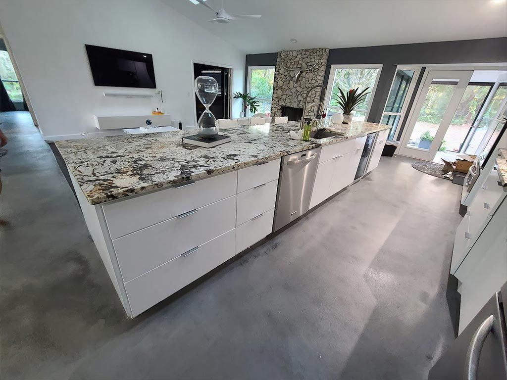 A kitchen with granite counter tops , white cabinets , stainless steel appliances and a large island.