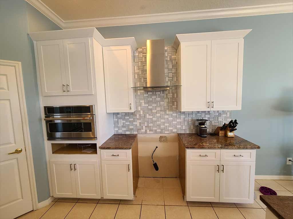 A kitchen with white cabinets , granite counter tops , and stainless steel appliances.