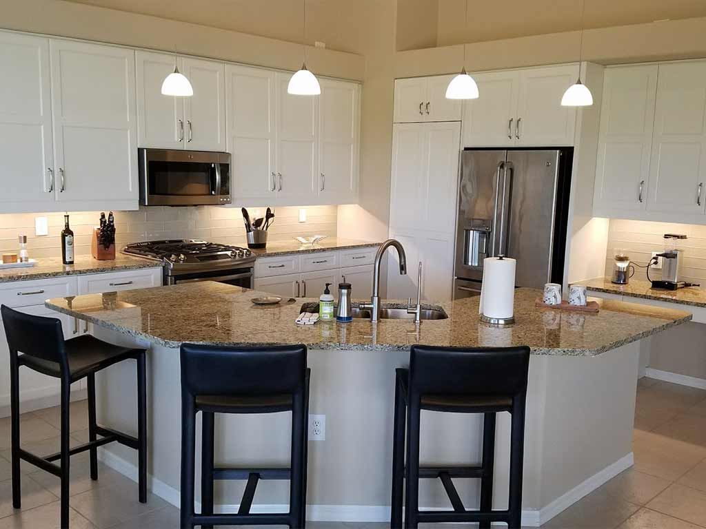 A kitchen with granite counter tops and white cabinets