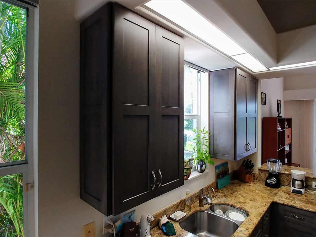 A kitchen with a sink , cabinets , and a window.