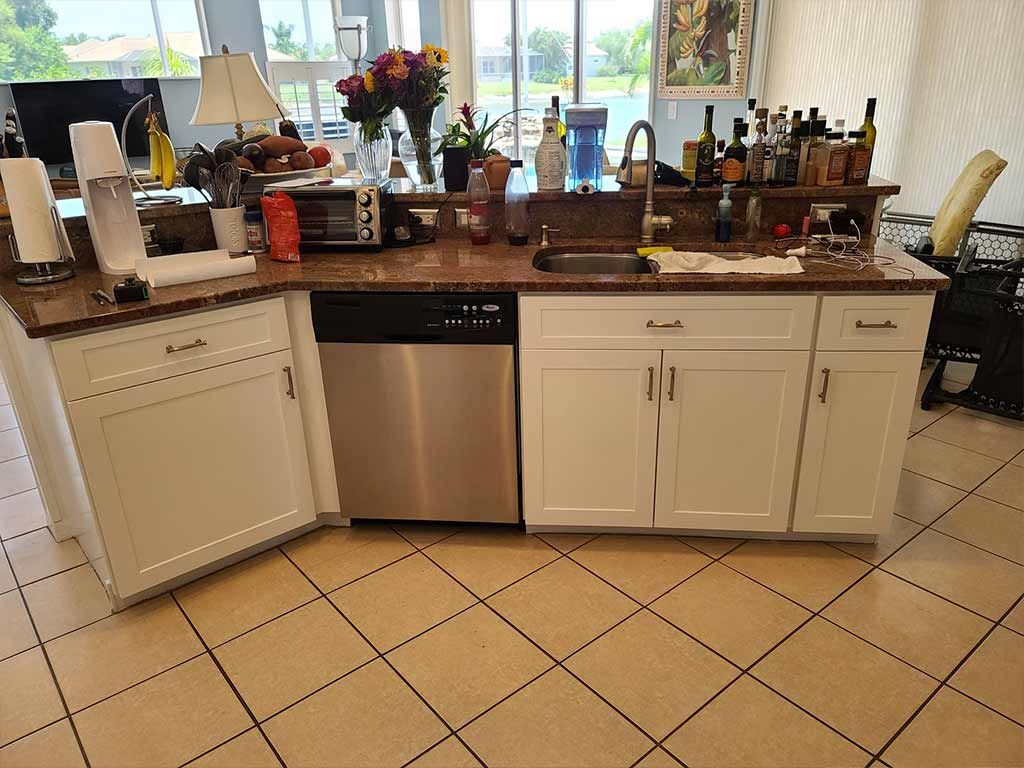 A kitchen with white cabinets , stainless steel appliances , a sink and a dishwasher.