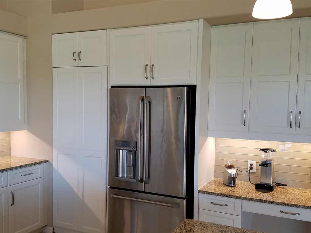 A kitchen with white cabinets and a stainless steel refrigerator.