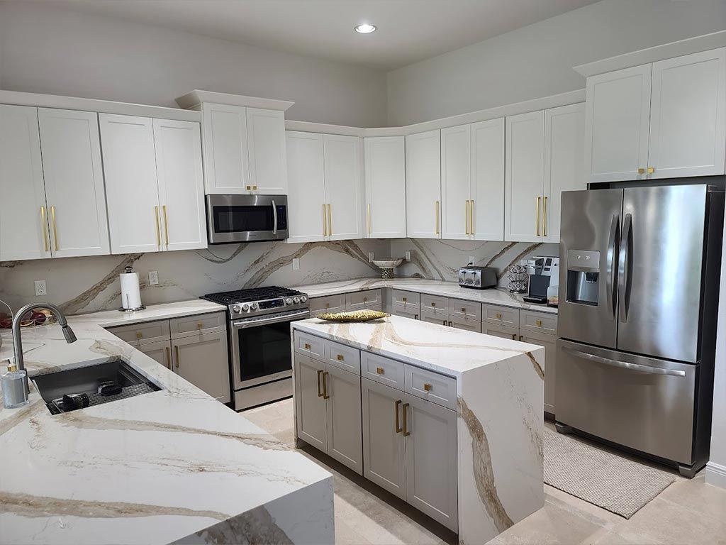 A kitchen with white cabinets , stainless steel appliances , and a large island.