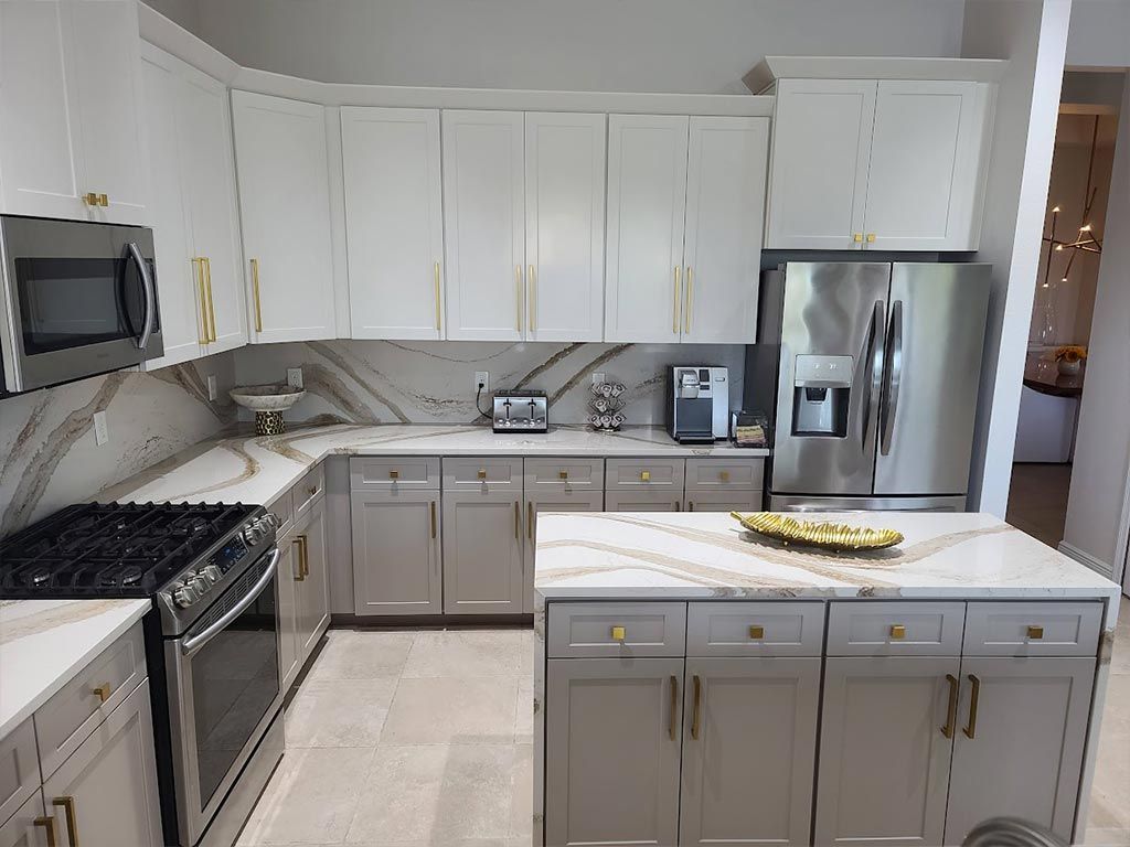 A kitchen with white cabinets , stainless steel appliances , and a large island.