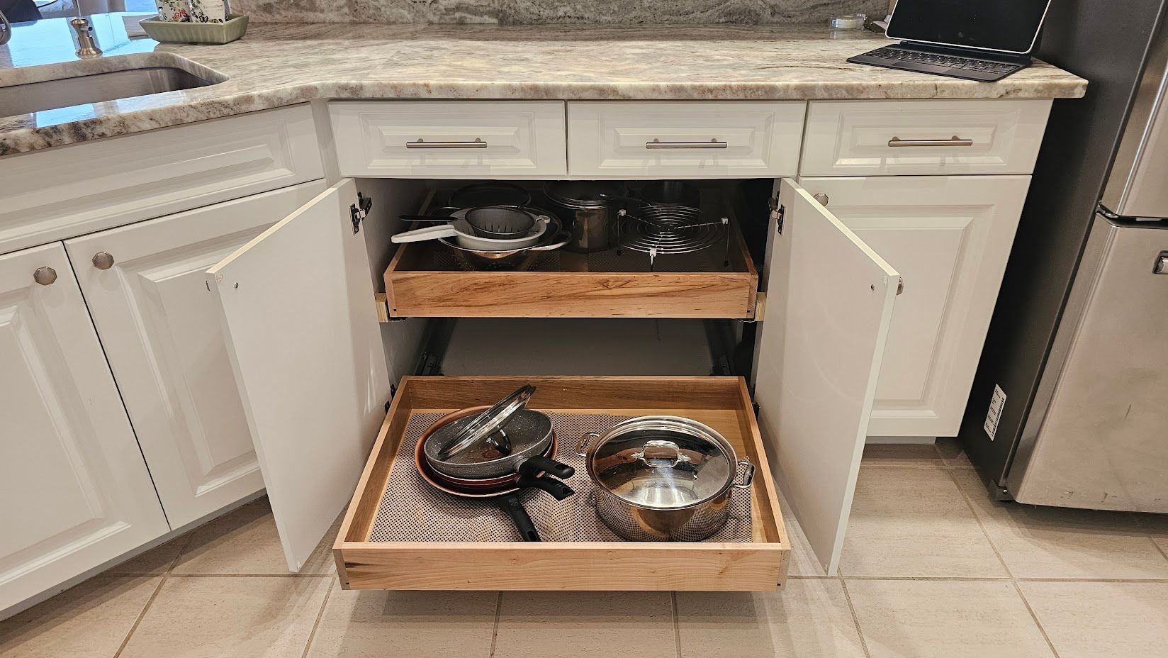 A kitchen with a pull out drawer filled with pots and pans.