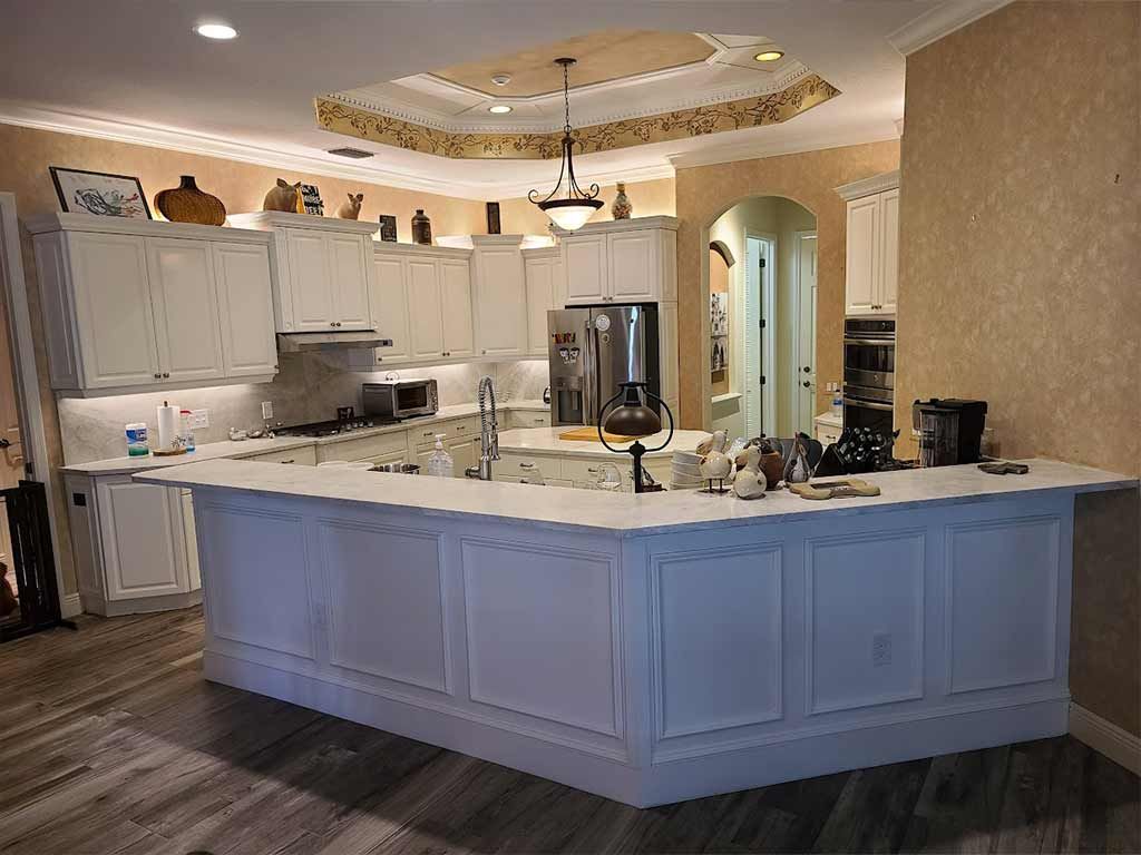A kitchen with white cabinets and a large island in the middle.