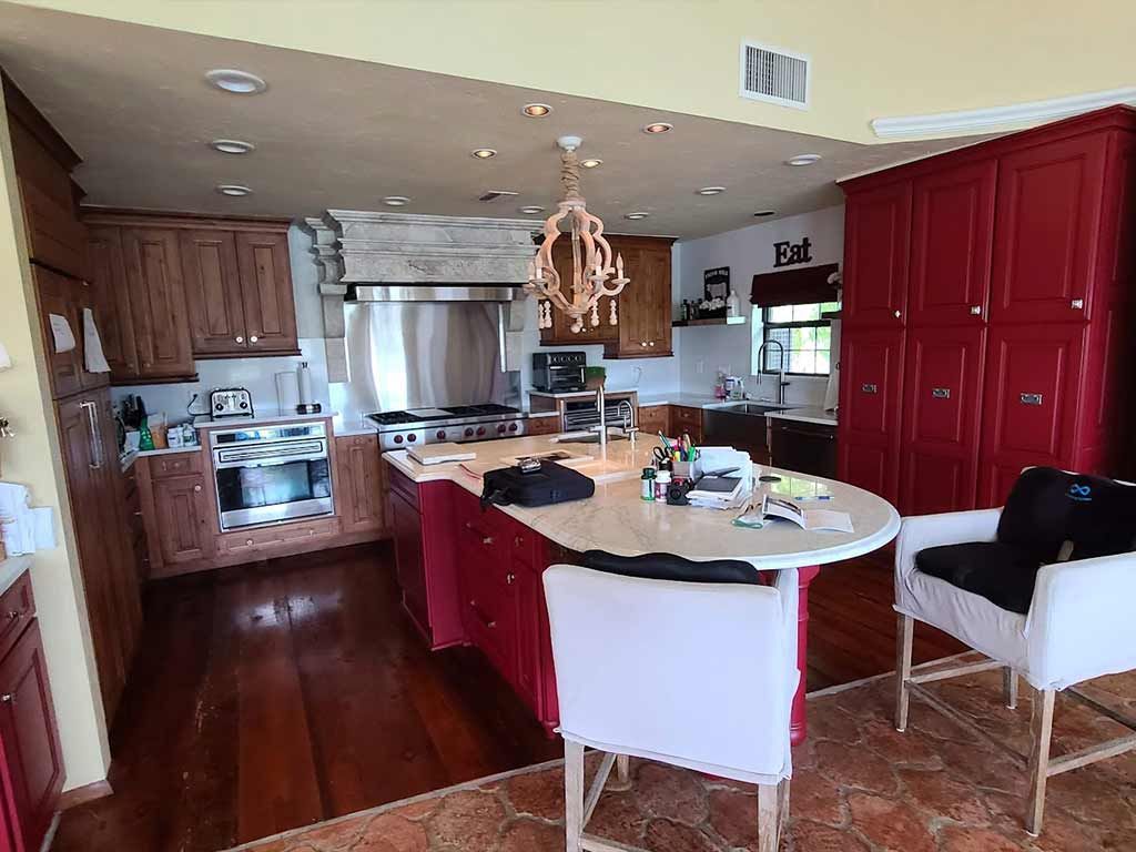 A kitchen with red cabinets , stainless steel appliances , a table and chairs.