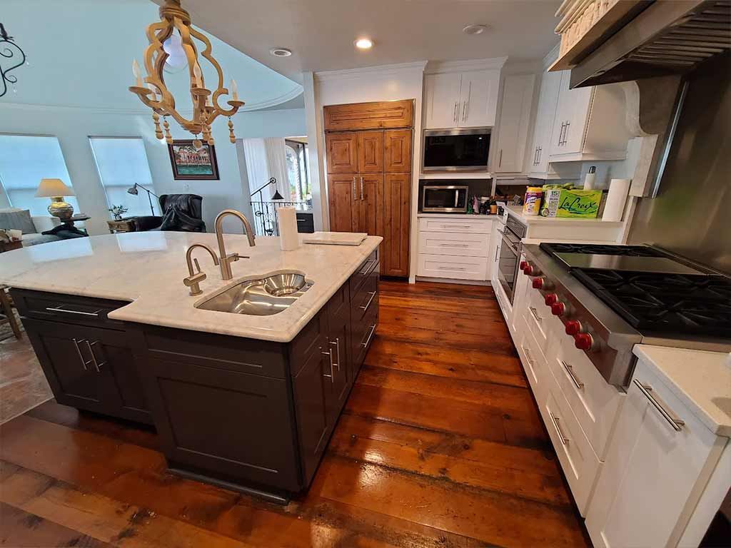 A kitchen with a large island , stove , sink , and cabinets.