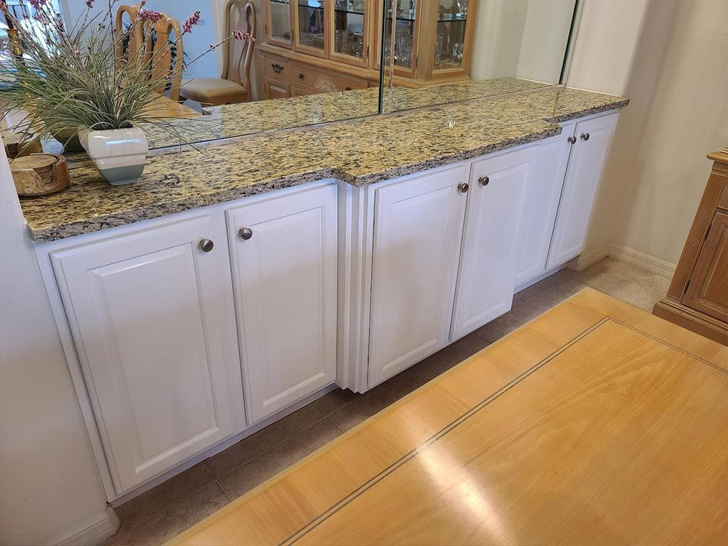 A kitchen with white cabinets and a granite counter top.