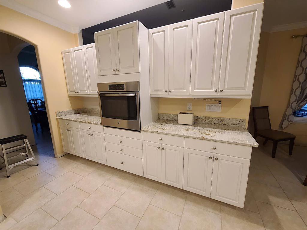 A kitchen with white cabinets and a stainless steel oven.