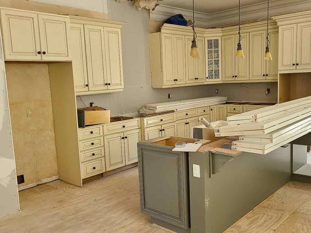 A kitchen under construction with white cabinets and a large island.
