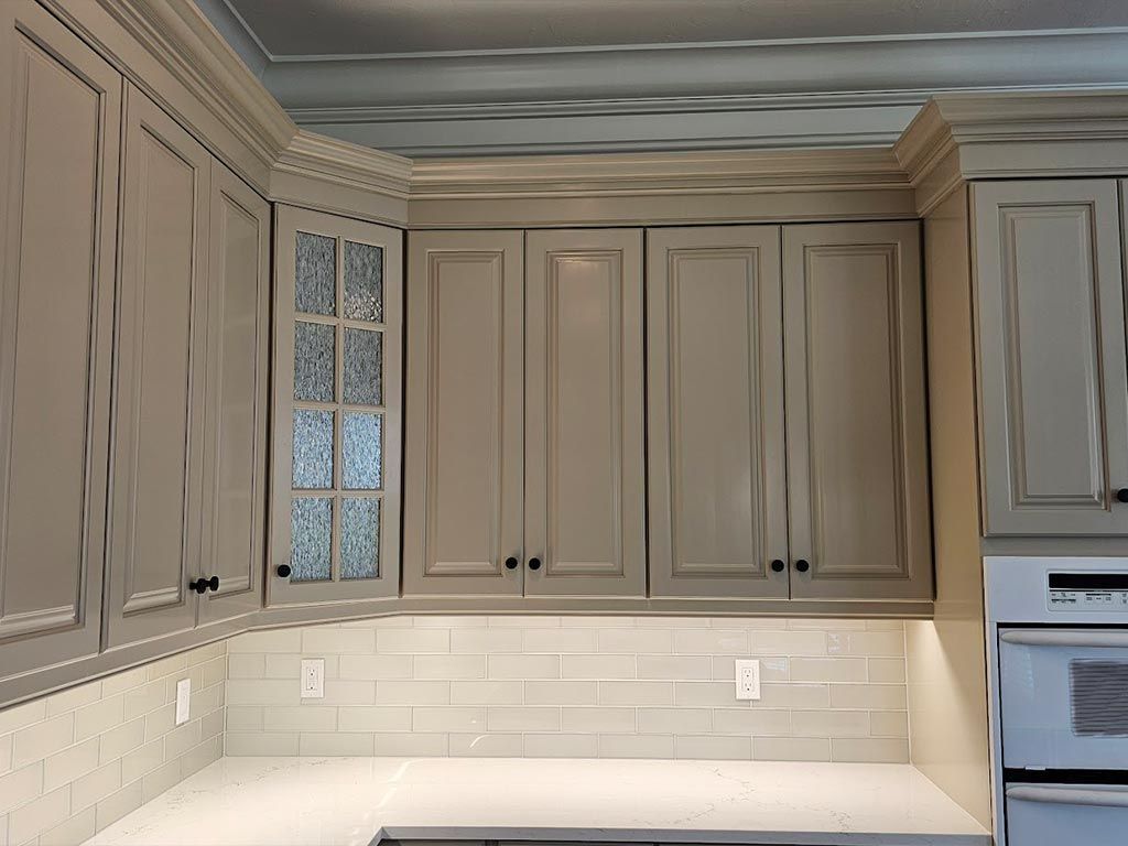 A kitchen with gray cabinets and white counter tops.