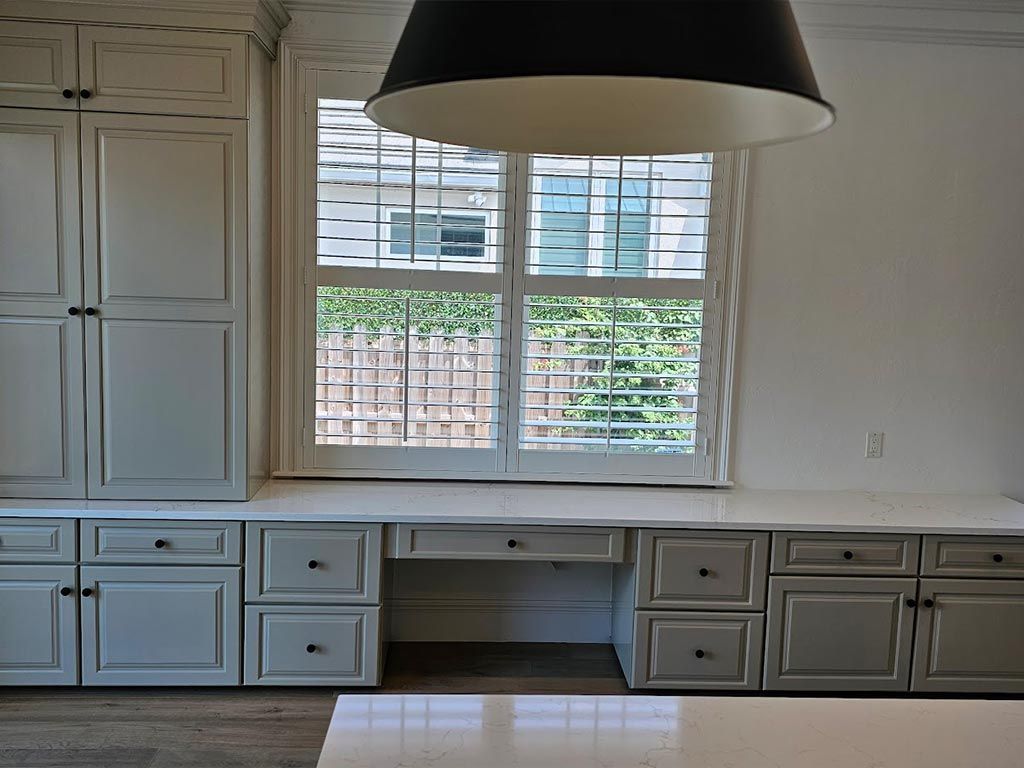 A kitchen with white cabinets and a large window