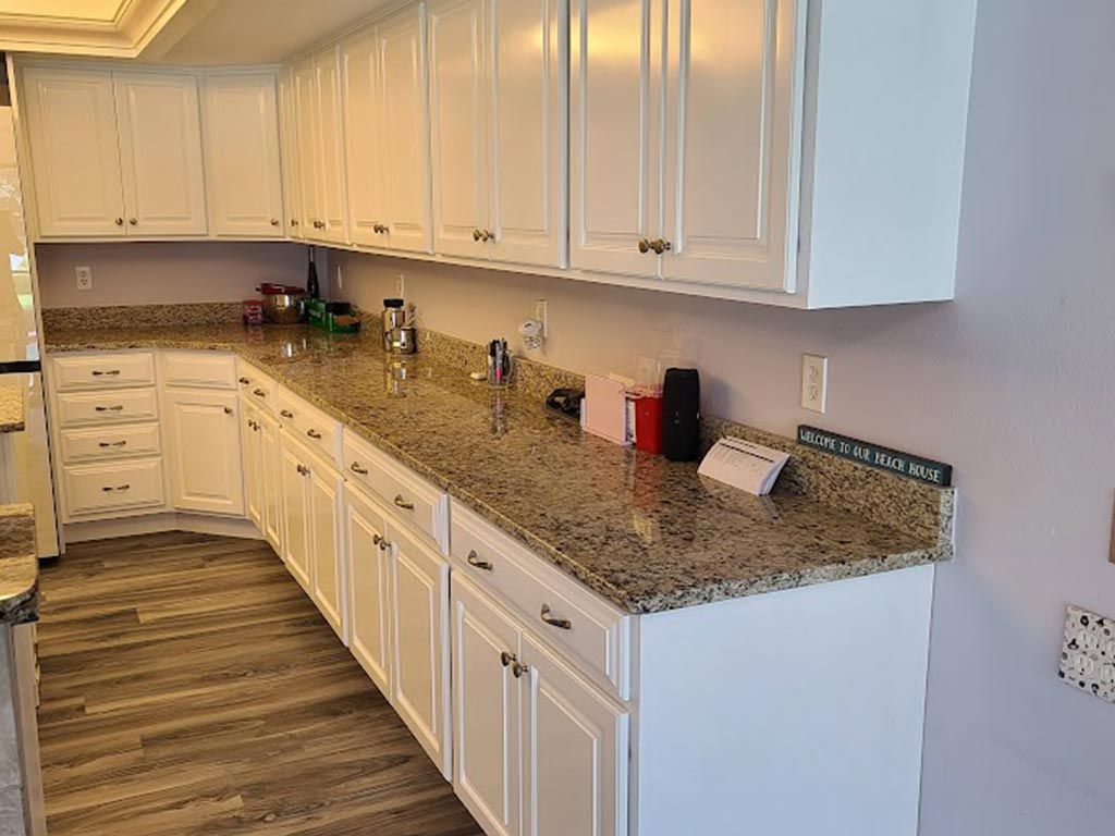 A kitchen with white cabinets and granite counter tops.