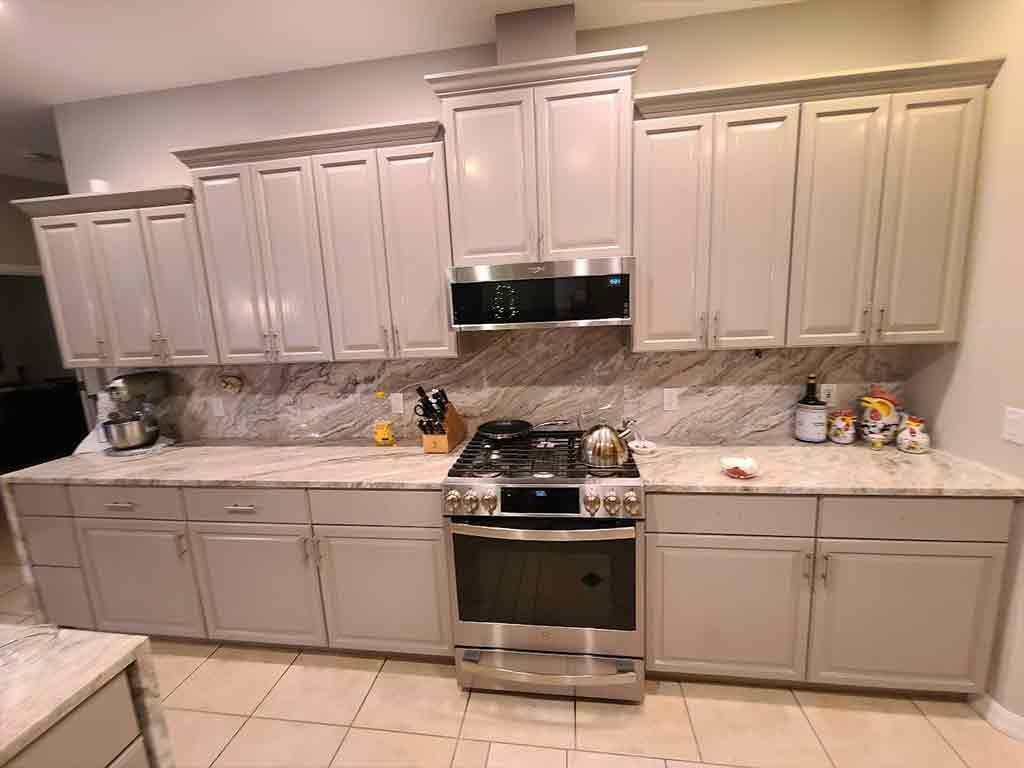 A kitchen with white cabinets , stainless steel appliances , and granite counter tops.