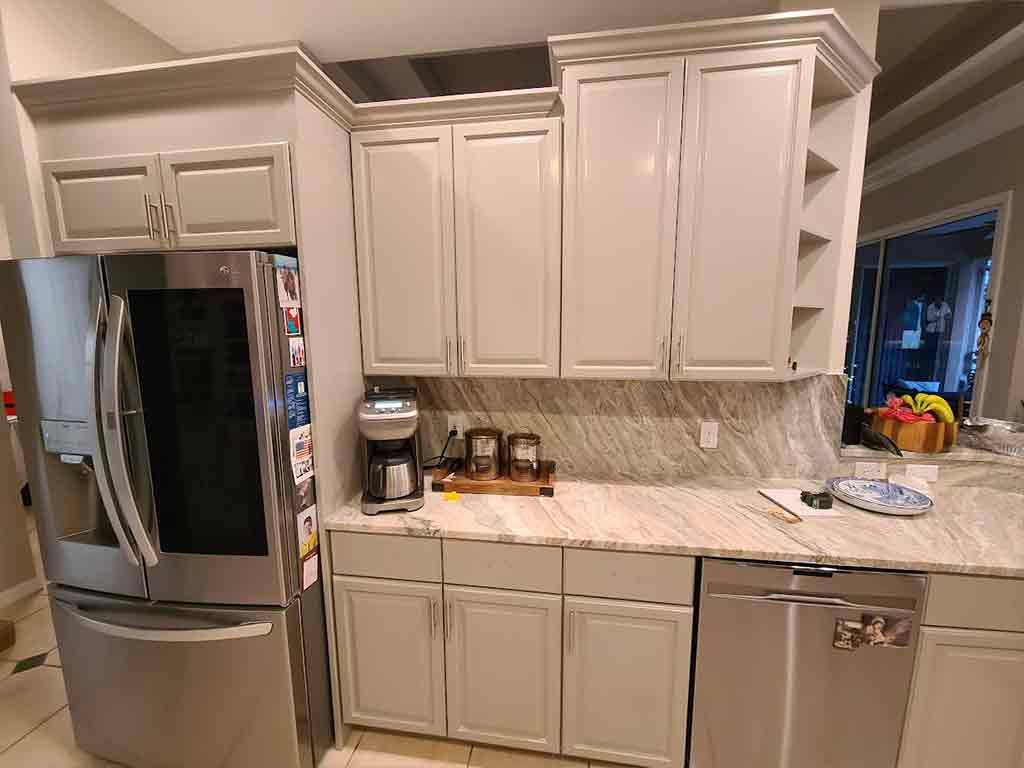 A kitchen with white cabinets , stainless steel appliances , a refrigerator and a dishwasher.