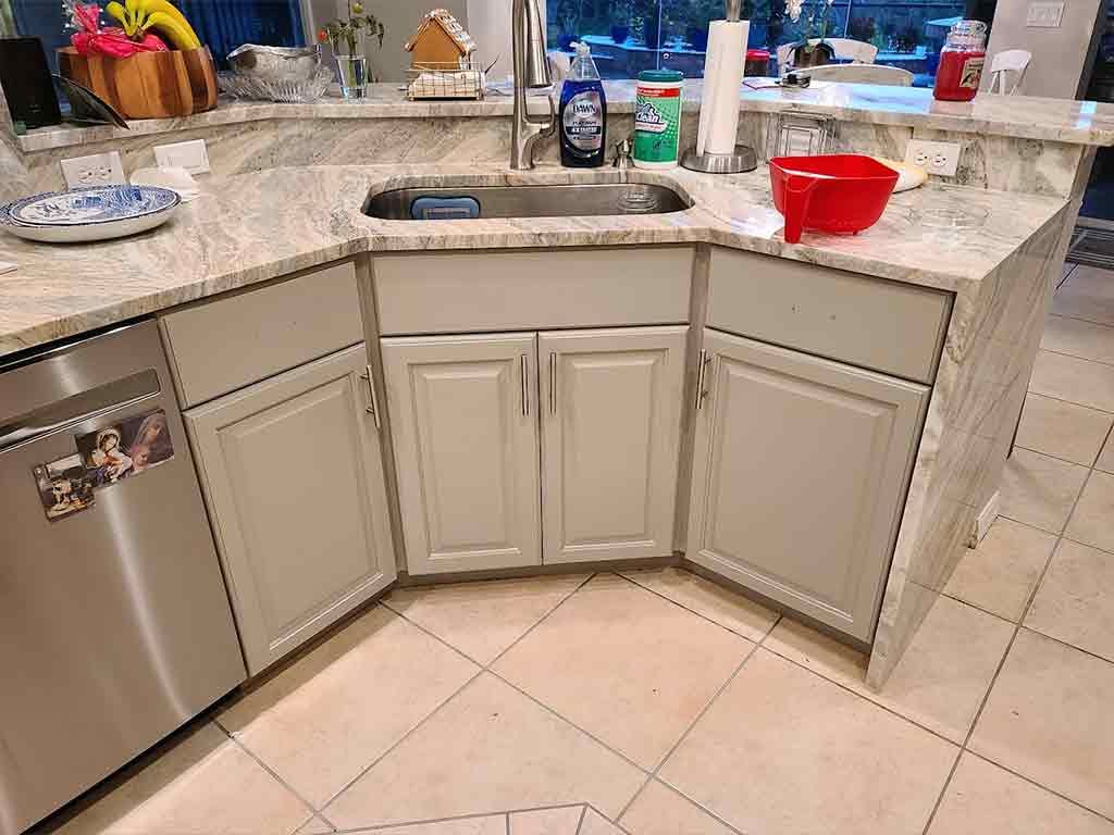 A kitchen with a sink , cabinets , and a stainless steel dishwasher.