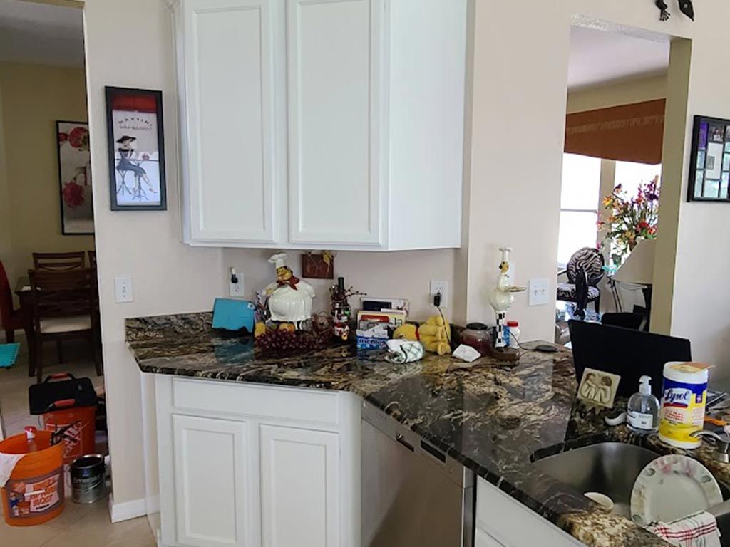 A kitchen with white cabinets , granite counter tops , and a sink.