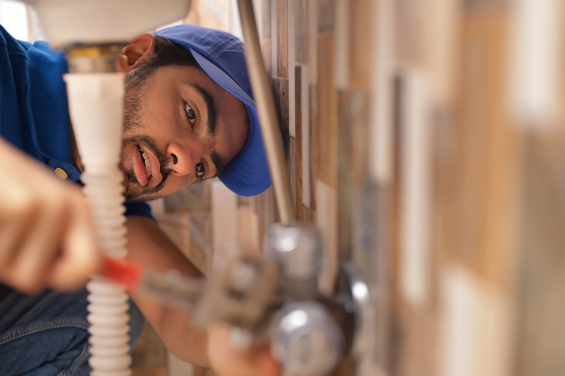 A man is fixing a sink with a pair of pliers.