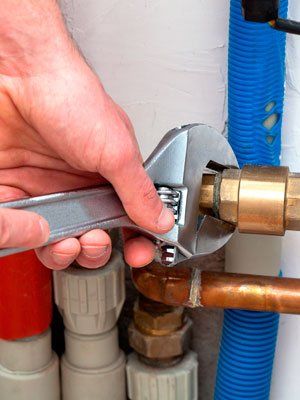 Hands with wrench - Plumbing service in Wellsville, NY