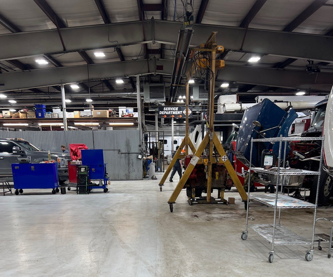 Yellow school buses inside a large garage; a person walks between them.