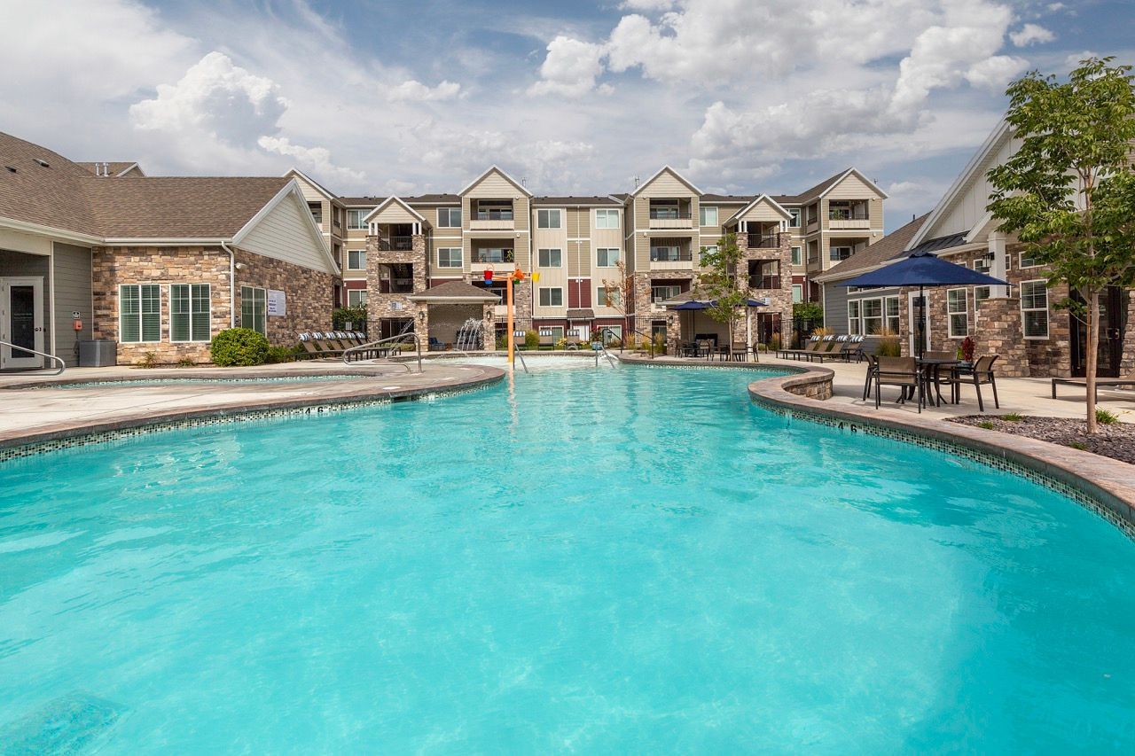 Outdoor pool at an apartment community with lounge chairs and surrounding buildings.