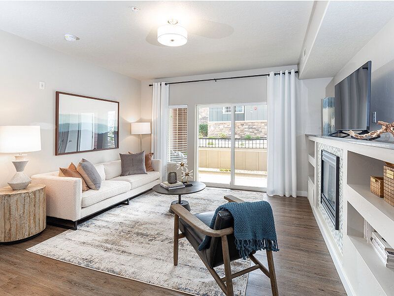 Bright apartment living room with sofa, chair, and balcony access.