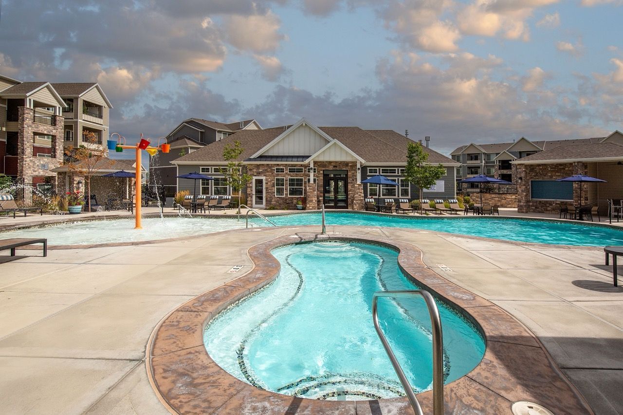 Outdoor community pool with lounge seating and a clubhouse in the background.